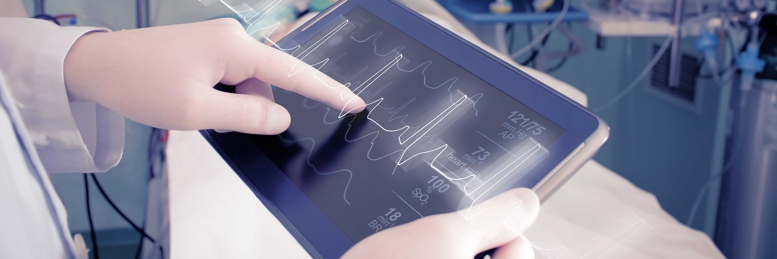 Healthcare provider pointing to a tablet monitoring a heartbeat.